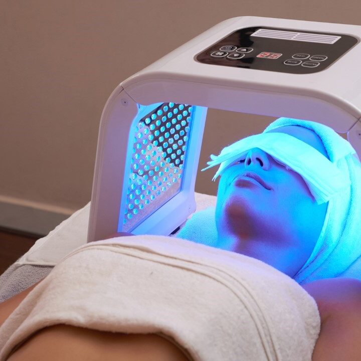 A woman getting her face painted with blue light.