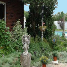 A garden with a statue of an angel in the middle.