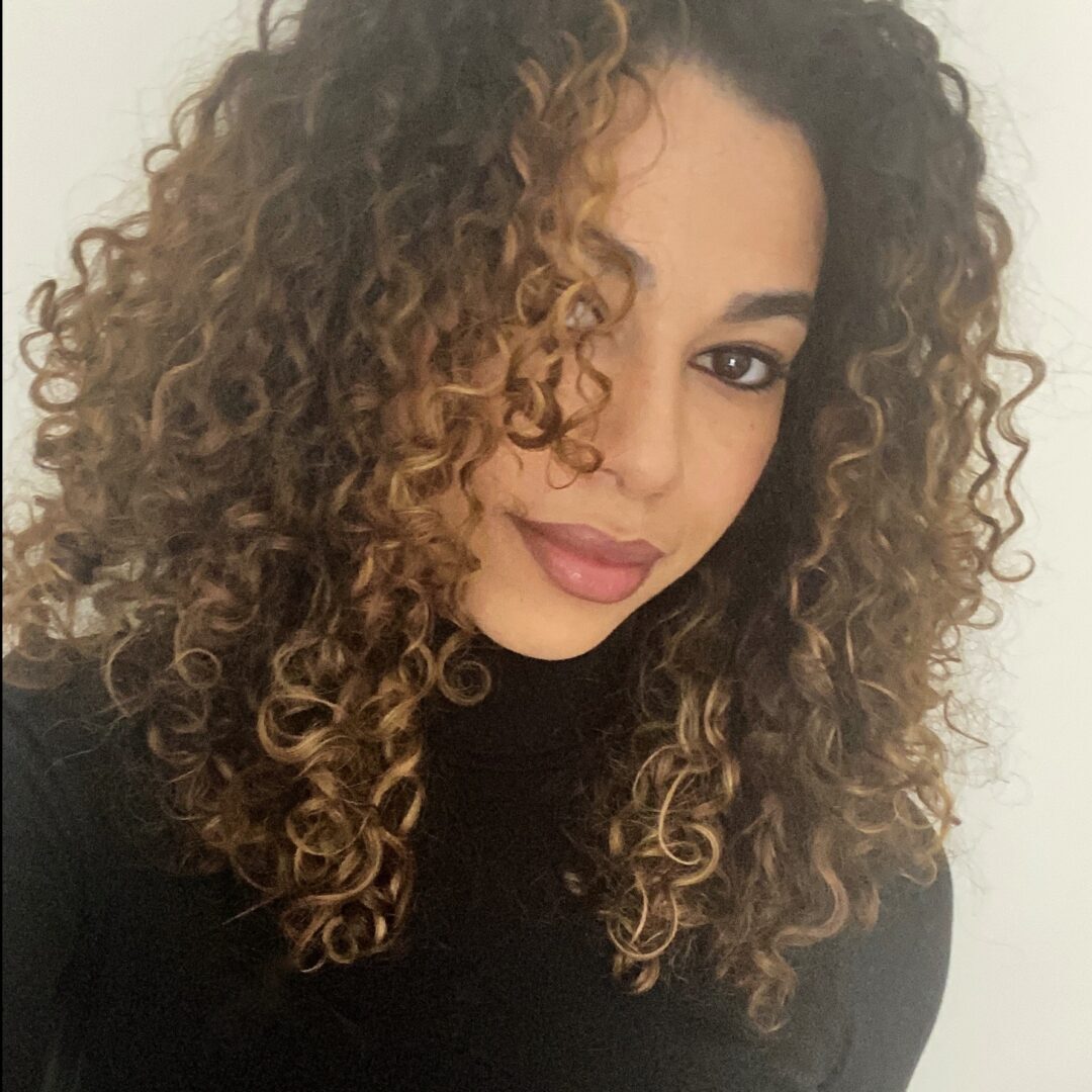 A woman with curly hair is posing for the camera.