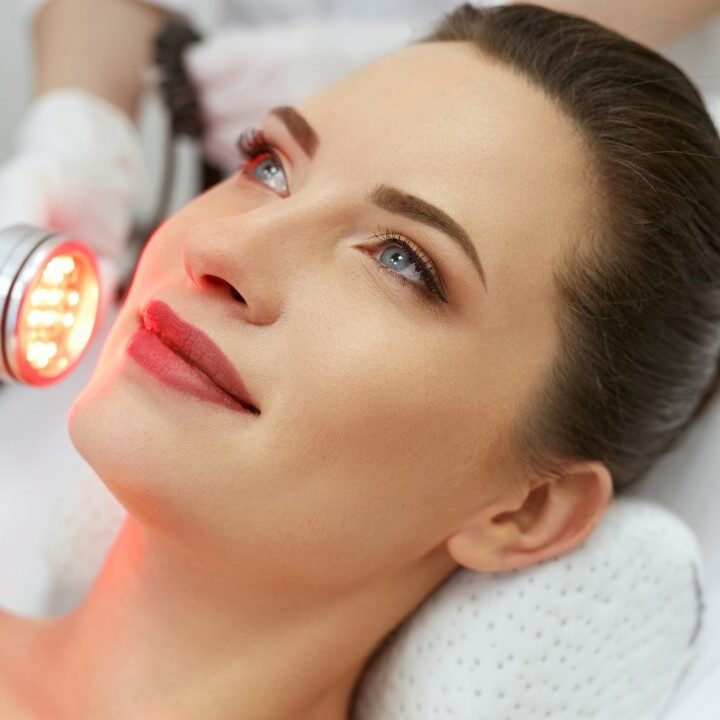 A woman getting her face illuminated by red light.