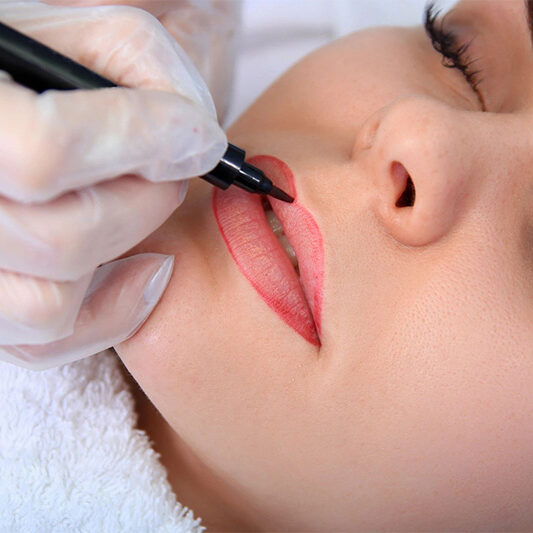 A woman getting her lips painted with a black marker.